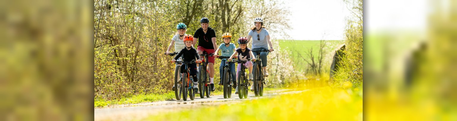 Maifeld-Radweg Gruppe von Radfahrer von Erwachsene und Kinder fährt durch eine blühende Landschaft