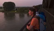 Zwei junge Frauen lehnen an dem Geländer auf der Urmitzer Rheinbrücke mit Blick auf den Sonnenaufgang.