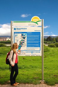 Eine Frau, die neben einem Wasserwegschild steht